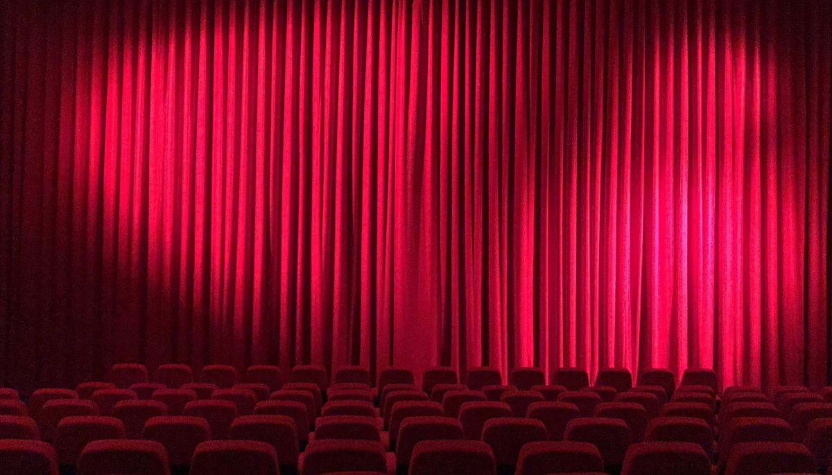 Theatersaal mit rotem Vorhang und roten Stühlen als Symbolbild für eine Theatervorstellung.