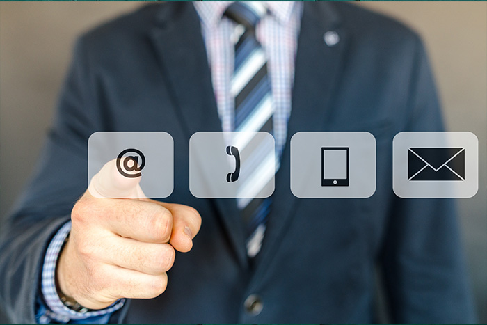Ansprechpartner, Mann zeigt auf verschiedene Symbole (Telefon, E-Mail, Mobil, Brief)