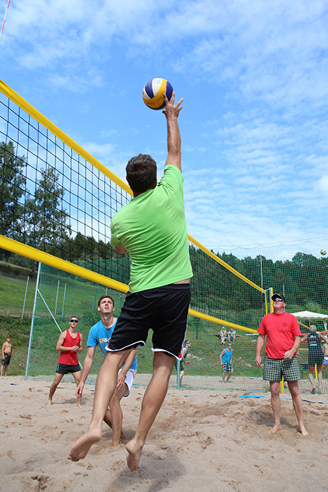 mehrere Personen spielen auf einem Sandplatz Beachvolleyball