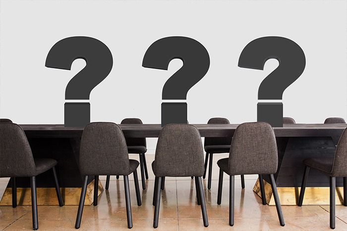 Konferenztisch auf dem 3 Fragezeichen stehen