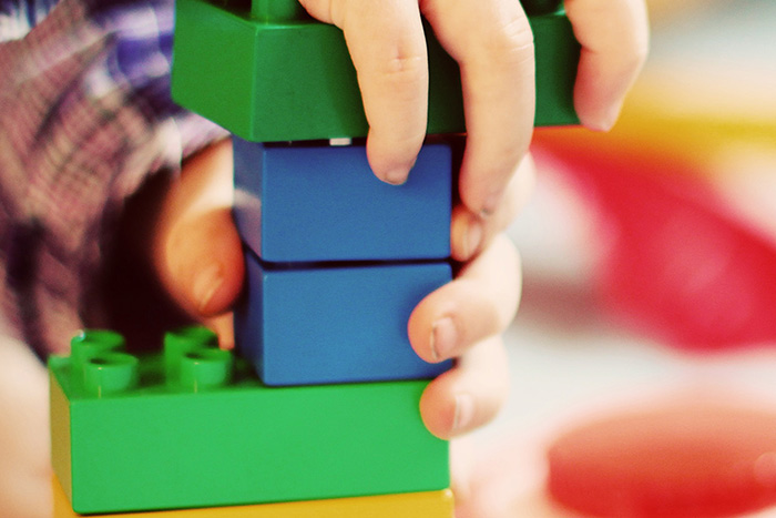 Bildausschnitt; Kinderhände spielen mit bunten Bausteinen