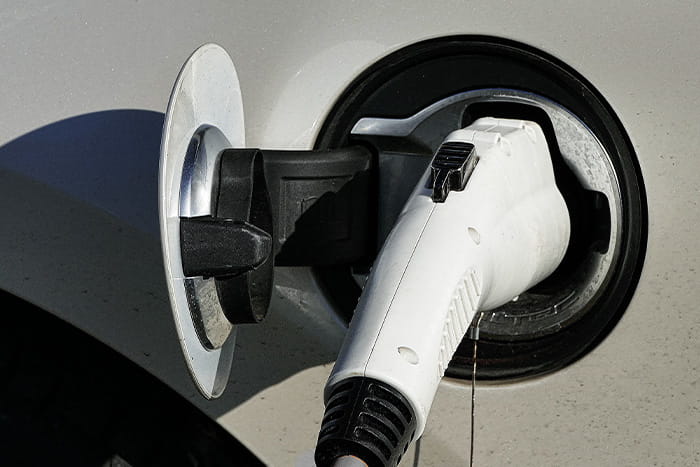 Ein Ladekabel zum Laden eines Elektroautos steckt in der Ladebuchse eines weißen Elektroautos