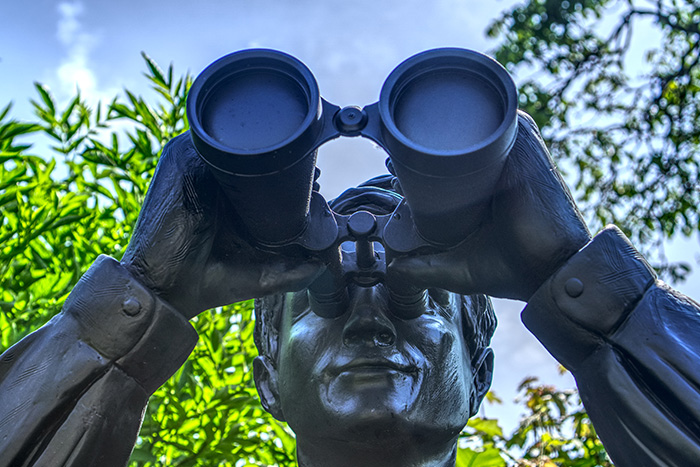 Bilsausschnitt: Eisenfigur eines Mannes der in ein Fernglas schaut