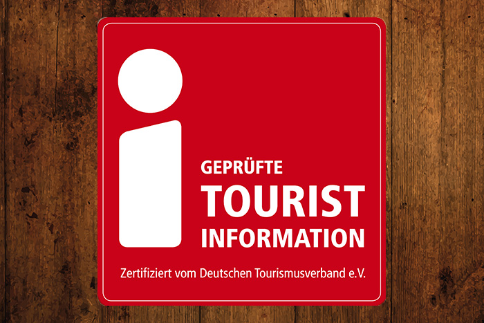 Holzhintergrund mit dem roten Schild der Touristinformation