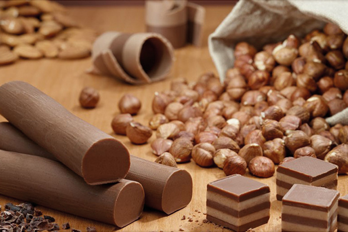 Viba Nougat Stange und würfelchen im Hintergrund Haselnüsse und Mandeln