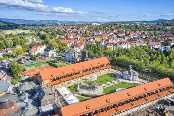 Luftaufnahme von Bad Salzungen mit dem Gradierwerk im Vordergrund, historischen Gebäuden, roten Dächern und einer grünen Parkanlage bei sonnigem Wetter.