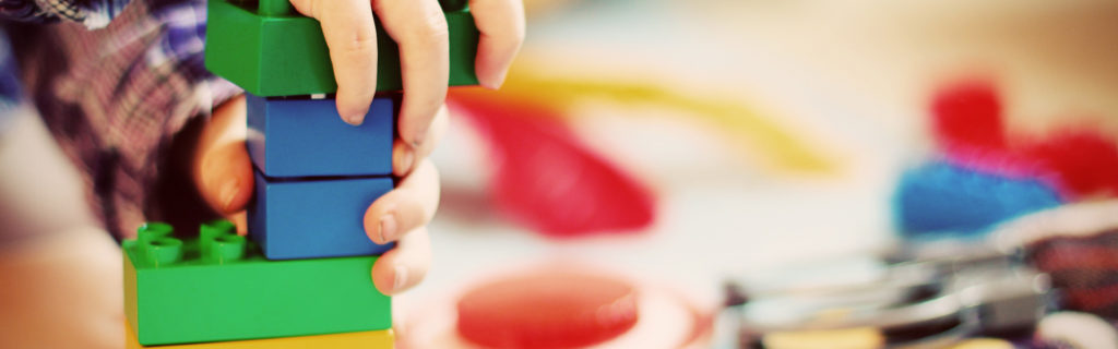 Bildausschnitt; Kinderhände spielen mit bunten Bausteinen