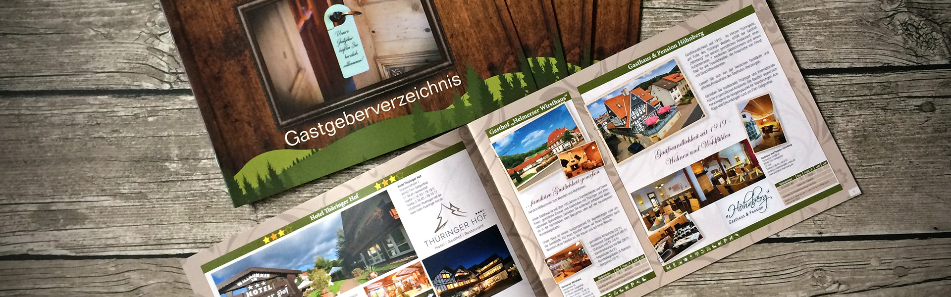 Das Gastgeberverzeichniseinmal aufgeschlagen und einmal unaufgeschlagen auf einer Holzplatte