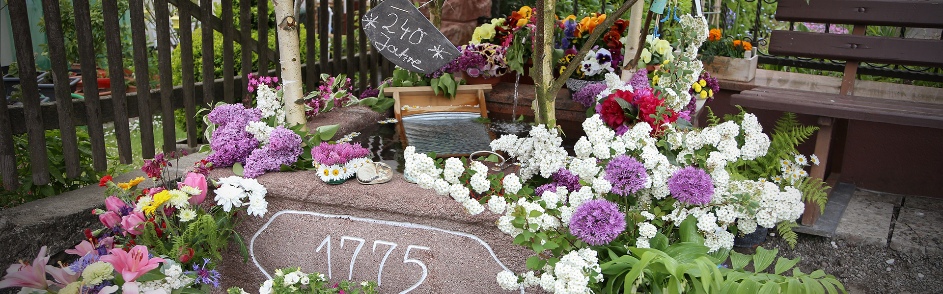 Brunnenfest: geschmückter Brunnen mit verschiedenen Blumensträußen in Floh-Seligenthal am Rennsteig