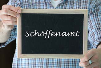 Tafel mit der Aufschrift Schöffenamt in den Händen einer Person