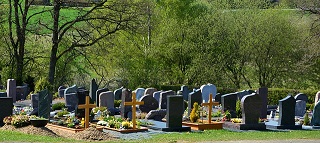 Blick auf den Friedhof mit Grabsteinen und Holzkreuzen